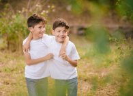 Heureux jumeaux garçons étreignant et regardant loin dans parc — Photo de stock