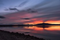 Lunga esposizione pittoresca vista del cielo nuvoloso tramonto sopra la montagna e l'acqua pacifica del lago in natura — Foto stock