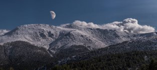 Vista mozzafiato ad ampio angolo della catena montuosa innevata contro il cielo serale con nuvole bianche e luna in natura — Foto stock