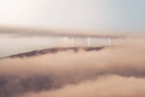 Вітряні млини сучасної вітроелектростанції, розташовані на пагорбі в туманний ранок в сільській місцевості — стокове фото