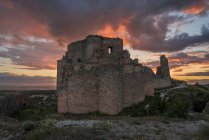 Visitar el castillo medieval en ruinas contra el cielo nublado al atardecer en el campo de Toledo - foto de stock
