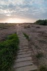 Shabby sentiero legname passando attraverso la campagna calma contro cielo nuvoloso tramonto — Foto stock