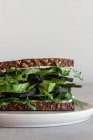 Closeup de delicioso sanduíche natural feito com pão integral torrada com ervas verdes frescas com pepino e abacate servido em prato branco contra fundo branco — Fotografia de Stock
