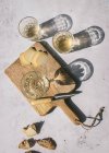 Composição de vista superior com copos de vinho servidos com queijo fatiado e pão com compota na mesa de mármore com placa de madeira à luz do sol — Fotografia de Stock