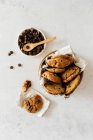 Вид зверху смачне домашнє солодке печиво в мисці, розміщене на мармуровому столі біля горщика з шоколадними чіпсами — стокове фото