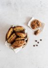 Vista dall'alto di deliziosi biscotti dolci fatti in casa in ciotola posizionati sul tavolo di marmo vicino alla pentola con gocce di cioccolato — Foto stock
