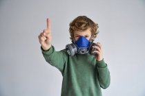 Ragazzo biondo, indossa un respiratore e mostra un dito — Foto stock