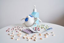 Breathing mask with antibacterial gel and pills with a thermometer on the bedroom table — Stock Photo