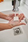 Mujer lavándose las manos en el fregadero de la cocina para evitar una posible infección - foto de stock