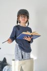 Блондин в пижаме со шлемом и книгой, играющей в исследования — стоковое фото