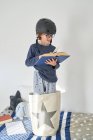 Garoto loiro de pijama com capacete e livro de pesquisa — Fotografia de Stock