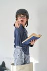 Blondes Kind im Schlafanzug mit Helm und Buch beim Recherchieren — Stockfoto