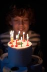 Loiro menino soprando as velas em seu papel higiênico bolo de aniversário — Fotografia de Stock