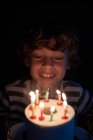 Loiro menino soprando as velas em seu papel higiênico bolo de aniversário — Fotografia de Stock