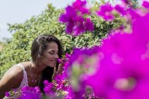 Jovem mulher bonita cheira uma flor no jardim — Fotografia de Stock