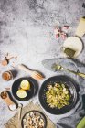 Зверху порція смачних смажених зелених брокколі з мигдалем на чорній тарілці на сірому столі в складі з різними інгредієнтами для приготування страви в домашніх умовах — стокове фото
