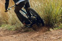 Back view of cropped unrecognizable man in helmet going downhill during mountain biking practice in wood forest — Stock Photo