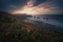 Великолепный пейзаж скалистого побережья и волн с беспокойным океаном на закате — стоковое фото