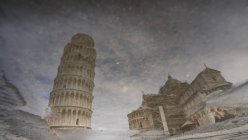 Amazing reflection of famous Leaning Tower of Pisa and Pisa Cathedral in puddle — Stock Photo