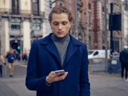 Стильний молодий чоловік переглядає на смартфоні на вулиці міста — стокове фото
