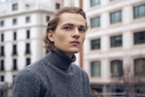 Moderno macho joven serio con corte de pelo elegante en suéter gris cálido - foto de stock
