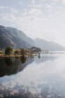 Живописный пейзаж спокойного озера в окружении скалистых гор, отраженных в воде в солнечный день с облачным небом в Шотландии — стоковое фото