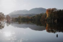 Malerische Landschaft eines ruhigen Sees, umgeben von felsigen Bergen, die sich bei sonnigem Wetter und bewölktem Himmel in Schottland im Wasser spiegeln — Stockfoto