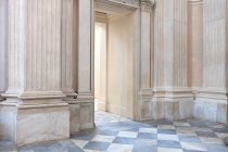 Porta e corredor rasgados dentro do edifício envelhecido com paredes de mármore ornamentais e piso em azulejos — Fotografia de Stock