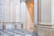 Porta e corredor rasgados dentro do edifício envelhecido com paredes de mármore ornamentais e piso em azulejos — Fotografia de Stock