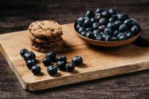 Blueberry and cookies on wooden board — Stock Photo