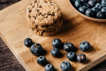 Blueberry and cookies on wooden board — Stock Photo