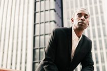 Homem de negócios negro confiante apoiando-se em trilhos — Fotografia de Stock