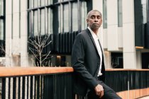 Selbstbewusster schwarzer Geschäftsmann stützt sich auf Geländer — Stockfoto