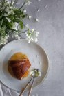 Vista superior de la deliciosa torta Bundt con salsa de manzana colocada en la mesa cerca de flores blancas y vela ardiente - foto de stock