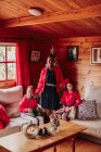 Cheerful young black female with cute laughing siblings in red clothes looking at camera while spending time together in cozy country house — Stock Photo