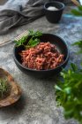 Da sopra vista dall'alto cipolle crude ed erbe poste sul tavolo grigio vicino alla ciotola con carne macinata sale in cucina — Foto stock