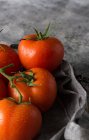 Von oben nass saubere Tomaten auf graue Stoffserviette auf grauem Betontischhintergrund gelegt — Stockfoto