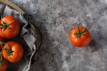 De cima de tomates limpos molhados colocados em guardanapo de tecido cinza sobre fundo de mesa de concreto cinza — Fotografia de Stock