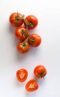 Вид сверху на пучок спелых натуральных помидоров и половинки помидоров на белом фоне — стоковое фото
