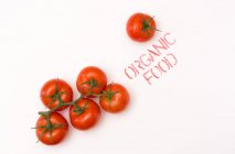 С верхней точки зрения чистый спелый помидор помещен рядом с органической пищей на фоне — стоковое фото