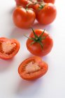 Vue du dessus du bouquet de tomates entières et coupées en deux sur fond blanc — Photo de stock