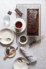 De cima gostoso bolo de banana e chocolate e xícara de chá fresco colocado na mesa perto de ingredientes e louça — Fotografia de Stock