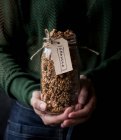 Pot en verre féminin méconnaissable de millet frais et de granola de quinoa avec étiquette — Photo de stock