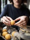 Crop unrecognizable female holding delicious cheese ball with mozzarella filling while sitting at table in cafe — Stock Photo