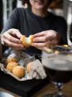 Ernte unkenntlich lächelnde Frau hält köstliche Käsekugel mit Mozzarella-Füllung, während sie am Tisch im Café sitzt — Stockfoto