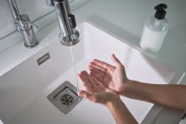 De cima vista superior cortada criança irreconhecível menino lavar as mãos sob água corrente com cuidado no banheiro moderno em casa — Fotografia de Stock