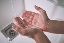 D'en haut vue recadrée méconnaissable enfant garçon se laver les mains sous l'eau courante soigneusement dans la salle de bain moderne à la maison — Photo de stock