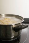 Gros plan de casserole en métal avec de l'eau bouillante et des pâtes maison placées sur le poêle dans la cuisine — Photo de stock