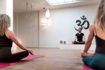 Visão traseira de mulheres calmas equilibradas e homem sentado na pose de lótus com mudra concentrado depois na aula de ioga — Fotografia de Stock