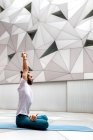 Дорослий бородатий чоловік у спортивному одязі сидить схрещеними ногами і роздумує із закритими очима та підняти руки під час тренування йоги в геометричній кімнаті — стокове фото